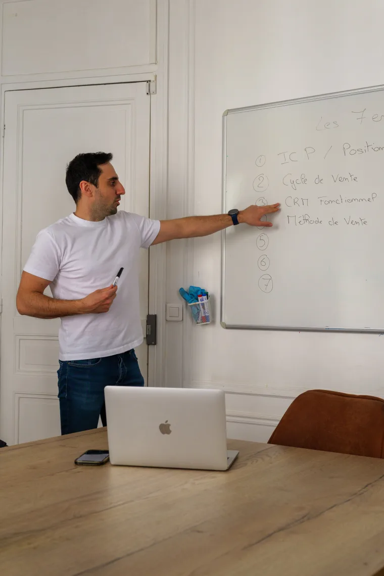 Julien Maslard animant une formation, pointant les 7 engrenages d'une machine commerciale au tableau